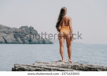 Woman sea yoga. Back view of free calm bliss satisfied woman with long hair standing on top rock with yoga position against of sky by the sea. Healthy lifestyle outdoors in nature, fitness concept.
