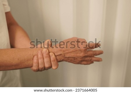 A woman uses her hand to hold the palm of her other hand to feel pain, pain, and tingling, combiningsymptoms of Guillain barre and numbness of the hand. Elderly woman tries to massage herself to relie