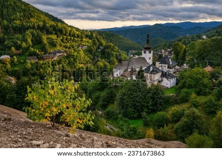Village Spania Dolina. Fall in Slovakia. Old mining village. Historic church in Spania dolina. Autumn colored trees at sunset. Royalty-Free Stock Photo #2371673863