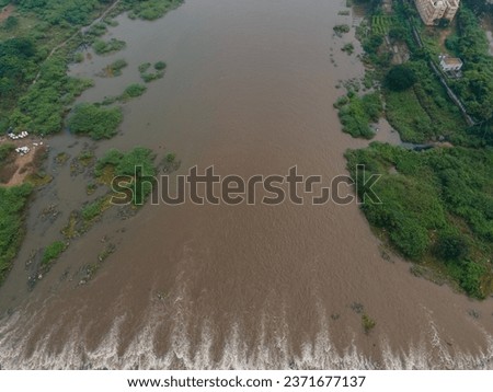 drone shot aerial view top angle panoramic photograph of massive river running through city riverbank flood water rain irrigation dam reservoir cityscape greenery agricultural fields fertile india 