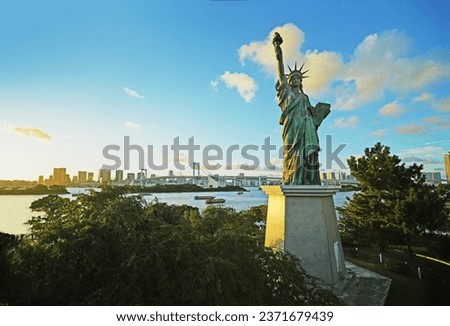 TOKYO, JAPAN – Closeup of copy of the Statue of Liberty, popular tourist attraction, located in Odaiba Marine Park, with views of the Rainbow Bridge the the Tokyo skyline.
