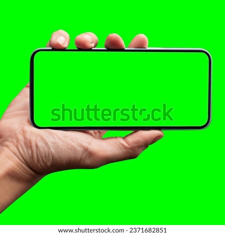 Image of hand holding a phone with a green screen in landscape orientation. on a green background.