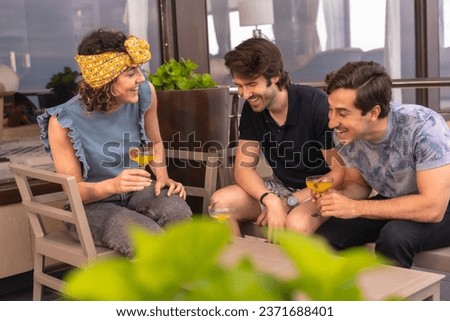 Three stylish and young adult friends celebrating holidays on a terrace of a bar