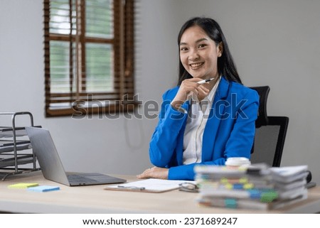 Asian busines or an accountant woman are analyzing data charts, graphs, and a dashboard on a laptop screen in order to prepare a statistical report and discuss financial data in an office.