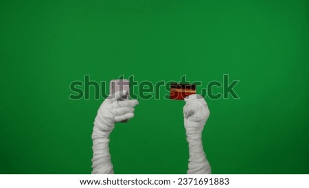 Detail green screen isolated chroma key photo capturing mummy's hands holding a smartphone and a credit card in its hands, encouraging to purchase, buy a product.