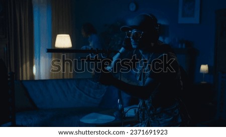 Medium-full photo capturing two ghost hunters entering a dark room in search for an entity that's making the lights flash, scanning the space with an EMF detector.