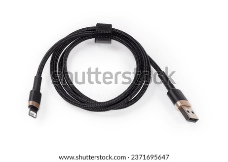 Coiled black braided cable with plugs USB Type-A and Lightning at the edges on a white background 
