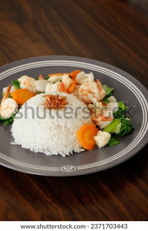 This is Nasi Cap Cay Seafood. Rice doused with cauliflower, carrots, bok choy, fish meatball, shrimp and then cooked in thick sauce. Selective focus.  Royalty-Free Stock Photo #2371703443