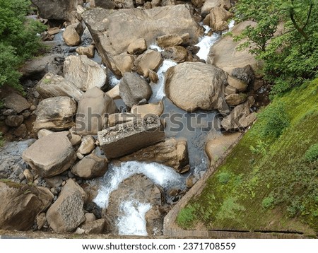s a close-up shot of a stream of water flowing over rocks. The image shows the natural landscape of an outdoor area with plants and moss surrounding the stream