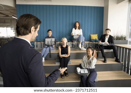 Business teacher, presenter man taking questions from small audience, giving lecture, training diverse employees. Trainee, intern, African student raising hand for asking Royalty-Free Stock Photo #2371712511