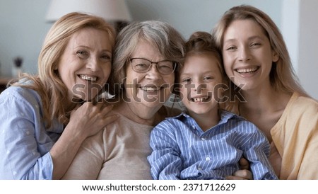 Happy pretty girl kid, young, mature, elderly women standing close, hugging, looking at camera, posing with toothy smiles. Four female family generations meeting head shot portrait. Banner shot