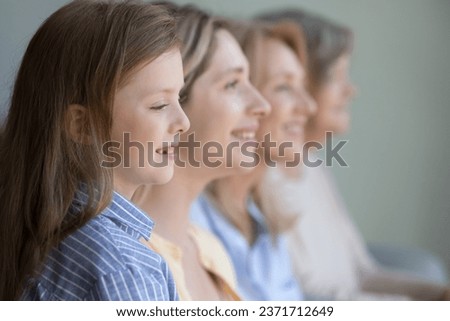 Happy pretty little Caucasian kid girl posing in line with young mother, senior grandmother, elderly great grandma, looking forward, thinking. Family portrait with four female generations, dynasty
