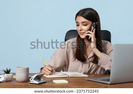 beautiful businesswoman in beige shirt using mobile phone