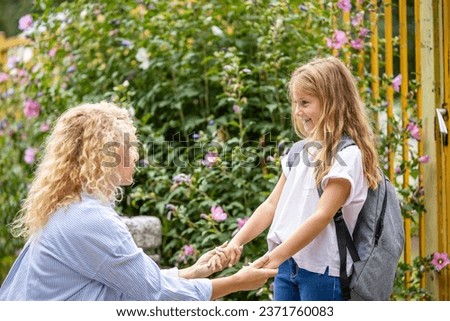 Mother and daughter holding hands together in front of the school.