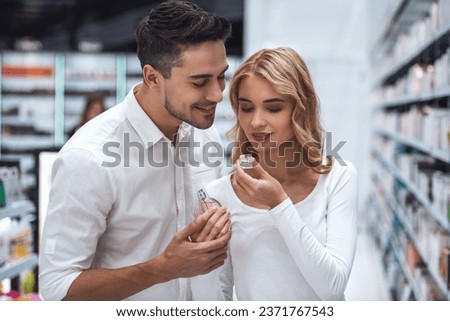 Beautiful couple is choosing perfumes and smiling while doing shopping in the mall Royalty-Free Stock Photo #2371767543