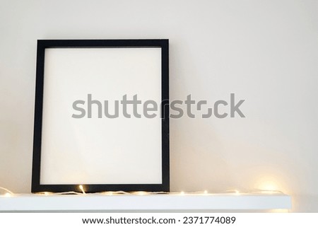 Blank wooden photo frame stands in the interior on a white background. Mockup poster frame close up in home interior. 