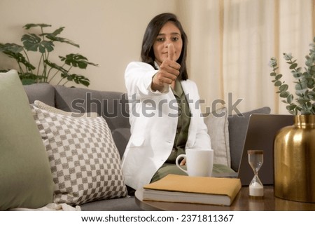 Woman doing positive gesture with hand, thumbs up.