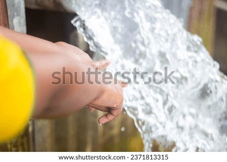 A boy pours water over his hands with both his hands