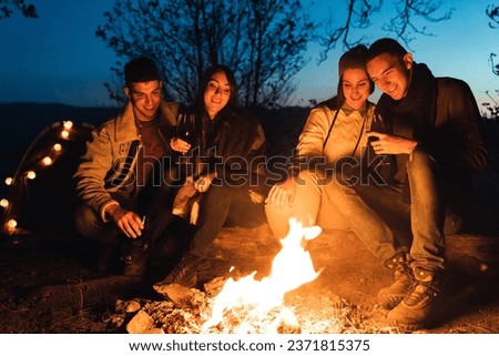 Two happy relaxed couples enjoying in their date night by the campfire. Group of four friends having a fun in the forest.