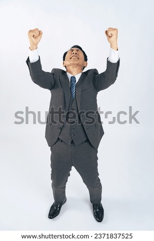 Asian middle-aged businessman in a business suit showing fists pumping. Royalty-Free Stock Photo #2371837525