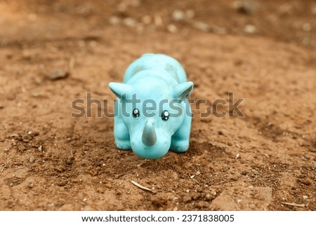 rubber rhino animal toy on the ground. blue toy rhinoceros