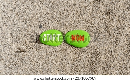 Start now symbol. Concept words Start now on beautiful green stone. Beautiful sea sand beach background. Business marketing, motivational start now concept. Copy space.
