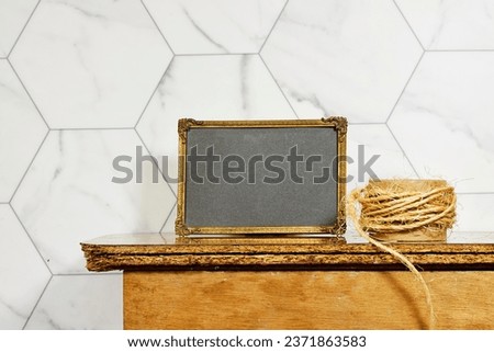 empty picture golden frame mockup with rope on wooden table. Elegant working space, home office concept. interior design