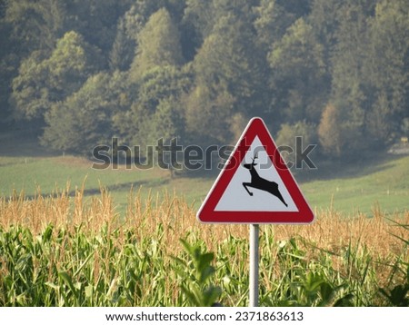 In the picture is a sign with a deer in front of corn field