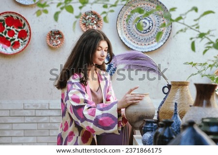 Beautiful woman, model, girl in national folk Uzbekistan fashion dress watching ceramics. Tashkent, Uzbekistan Royalty-Free Stock Photo #2371866175