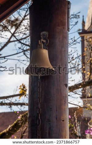 Old bell hanging on a wooden pole in the street of the city