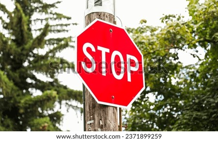 red stop sign on urban street corner, symbolizing road safety and traffic regulations. Clear blue sky in background, space for text