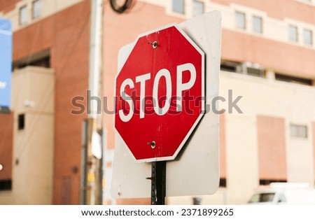 red stop sign on urban street corner, symbolizing road safety and traffic regulations. Clear blue sky in background, space for text