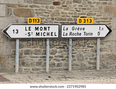 road signs with directions to Mont Saint Michel at 13 km and other locations in France