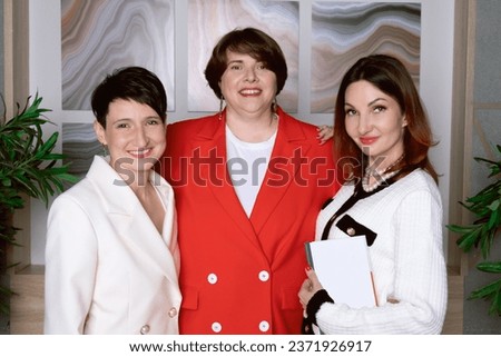 Three women business partners smile and look at the camera. Portrait of middle-aged female partners. Successful women entrepreneurs.