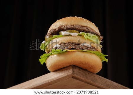 perfect tasty big double burger on wooden table on brown background, bottom view Royalty-Free Stock Photo #2371938521