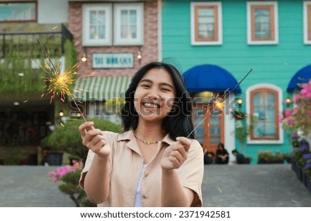 portrait of beautiful happy young asian woman holding sparklers fireworks to celebrate new year eve with garden party standing in outdoor vintage house yard