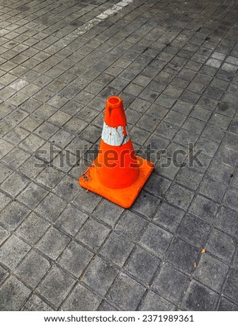 An orange traffic cone placed in the parking area functions as a road divider and warning for vehicles