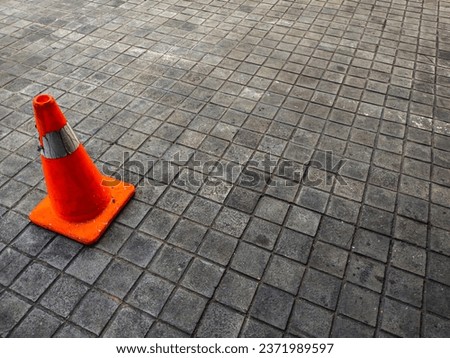 An orange traffic cone placed in the parking area functions as a road divider and warning for vehicles