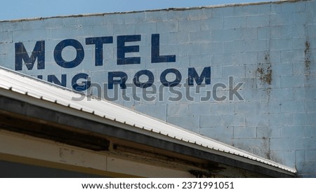 Old, dilapidated building featuring faded lettering on a wall