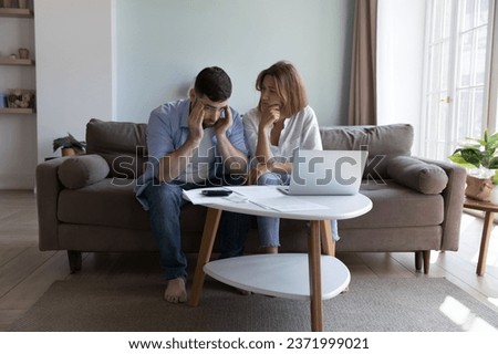 Tired concerned millennial couple thinking over high expenses, mortgage, rental, loan, tax fees, bankruptcy, money problems, financial crisis, bad news, using laptop, calculator at home Royalty-Free Stock Photo #2371999021