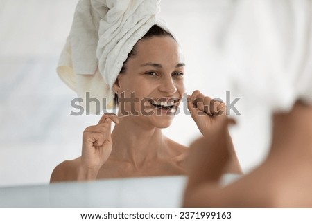 Smiling young woman after shower look in mirror in bathroom clean cleanse teeth with dental floss, happy girl take care or oral hygiene, prevent gingivitis or caries, dentistry, healthcare concept Royalty-Free Stock Photo #2371999163