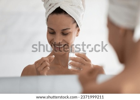 Smiling girl after shower use daily dose on vitamins, have supplements or drugs with water in bathroom, happy young woman hold meds take contraception pill at home bath, healthcare concept Royalty-Free Stock Photo #2371999211