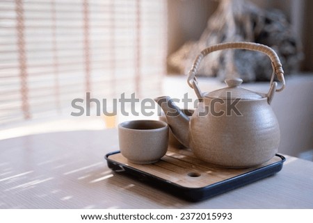 Teapot and tea cups, tea set on a tray placed on the table, blurred background, morning light.