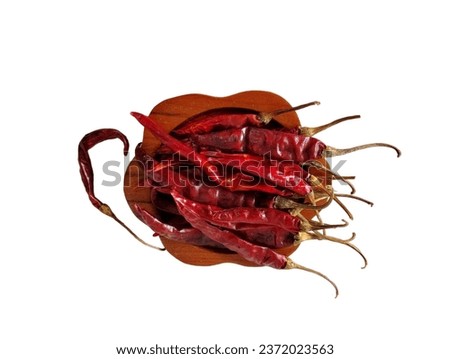 A white background has a handful of dried red chilies in a brown wooden tray in the center of the picture.
