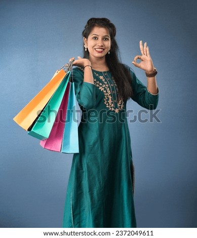 Beautiful Indian young girl holding and posing with shopping bags on a grey background