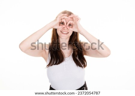 cheerful young woman making binocular hand sign with fingers on face