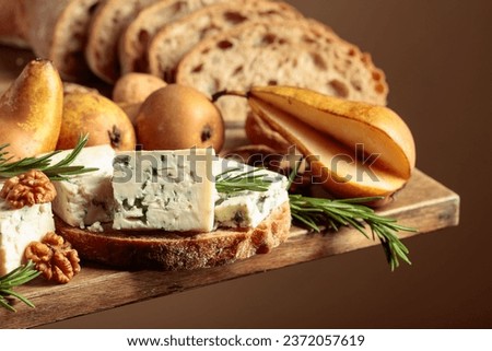 Sandwich with blue cheese and pears. On an old wooden table bread, blue cheese, pears, walnuts, and rosemary.