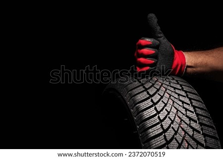 Car tire service and hands of mechanic holding new tyre on black background with copy space for text Royalty-Free Stock Photo #2372070519