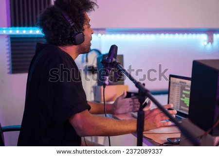 Side view of a musician recording a podcast from a studio