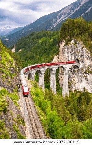Swiss red train on viaduct in mountain, scenic ride Royalty-Free Stock Photo #2372100115